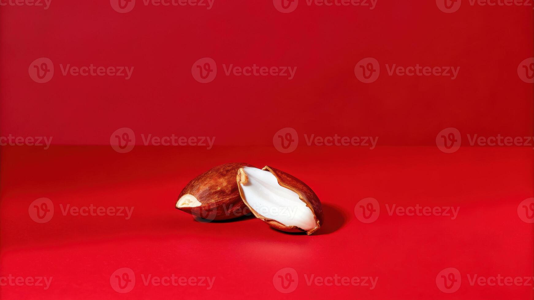 Studio shot of a single almond cracked open vibrant red background food photography close-up perspective photo