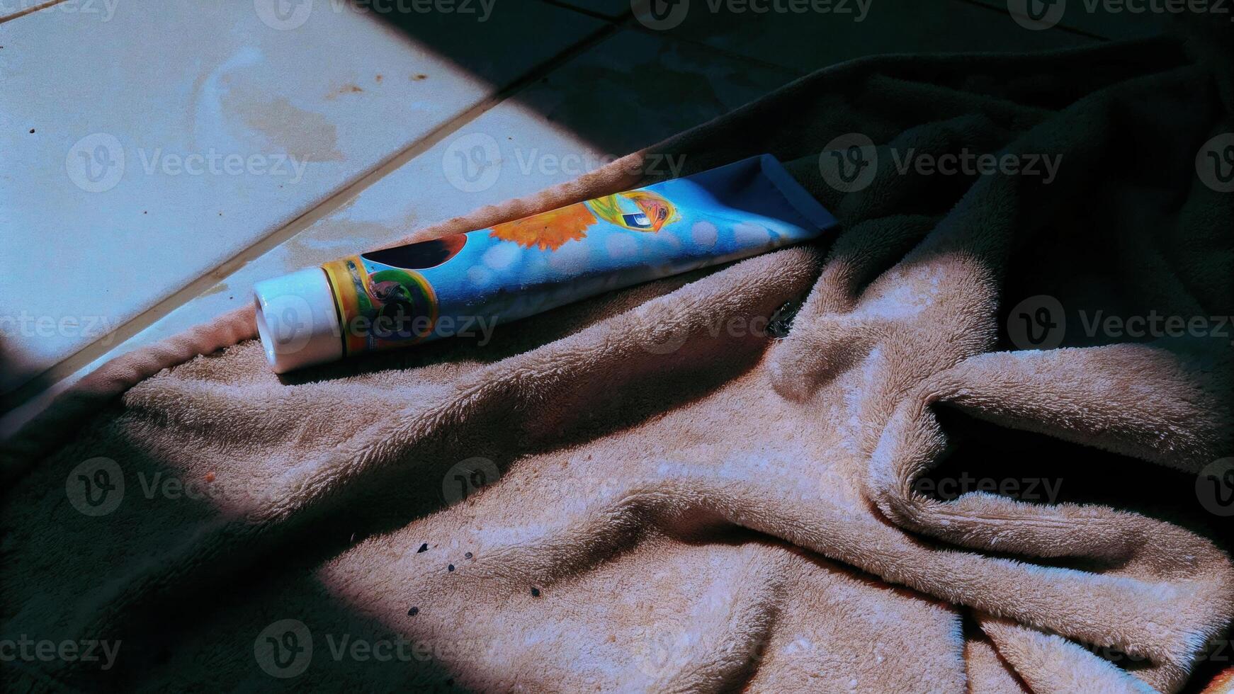 Children's wet toothpaste tube on colorful towel in bright environment capturing moisture details photo