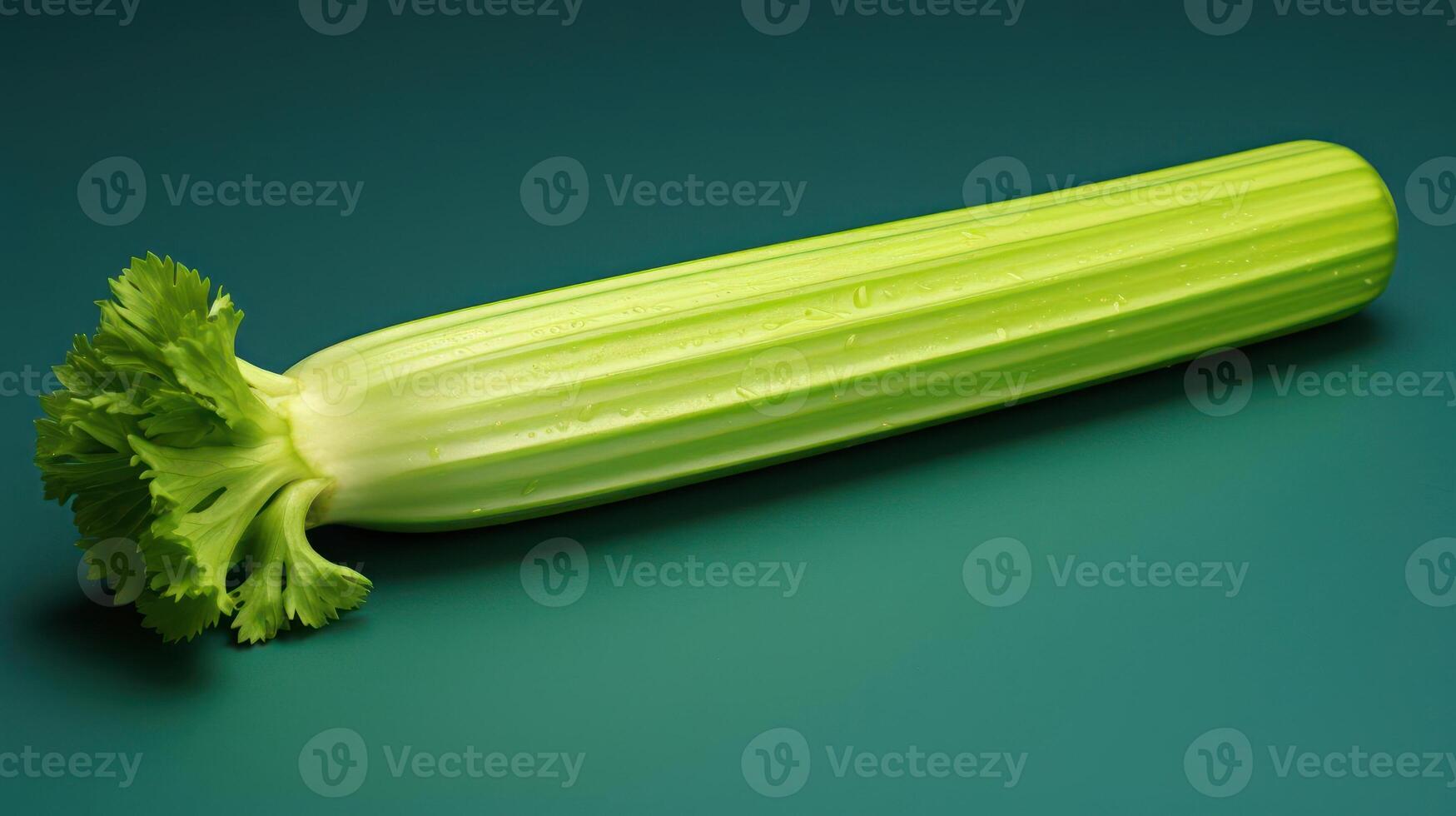 Fresh celery stalk with vibrant green leaves against a teal background. photo