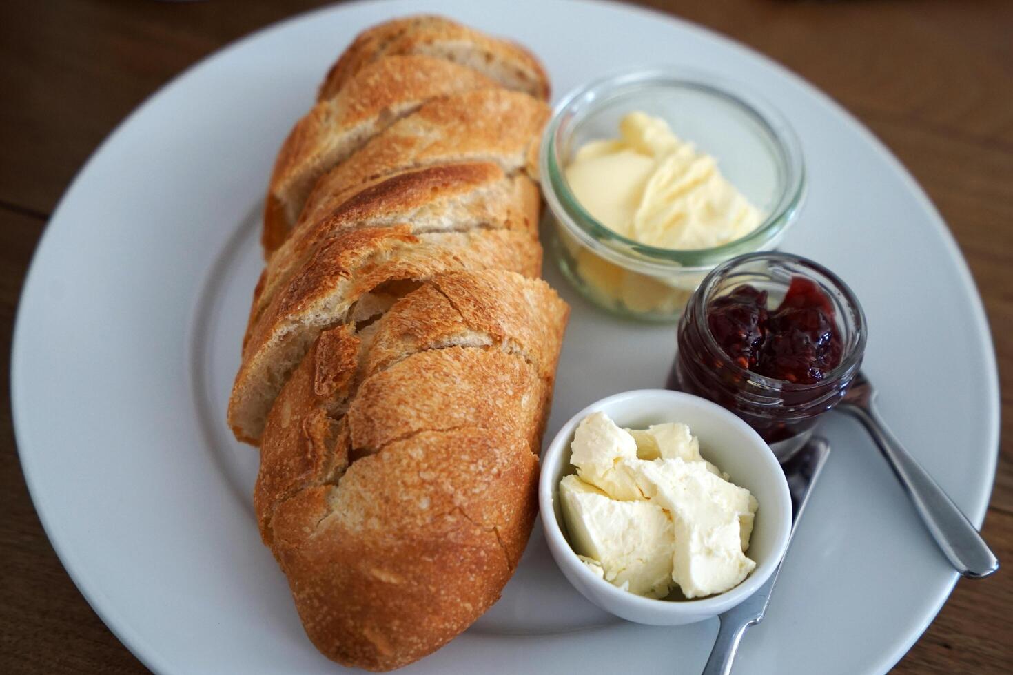 Close up plain Baguette served with butter clotted cream cheese and berry jam photo