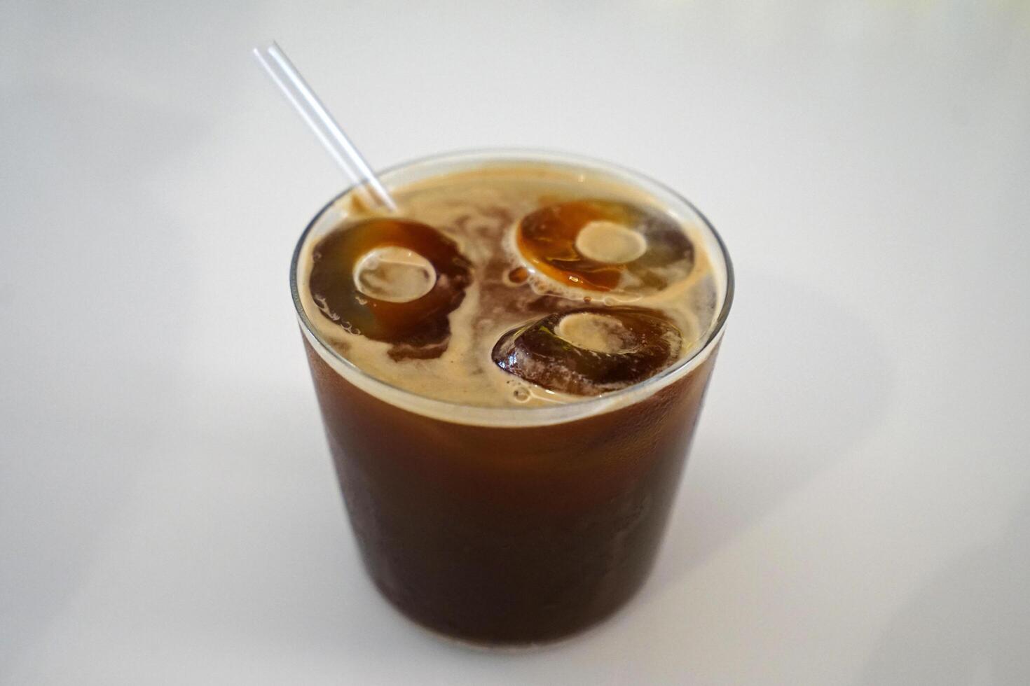 Close up glass of iced black Americano coffee on white table photo