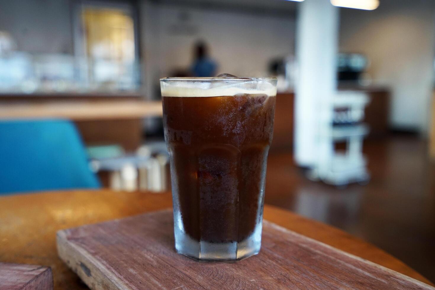 Glass of iced black coffee on wooden tray table photo