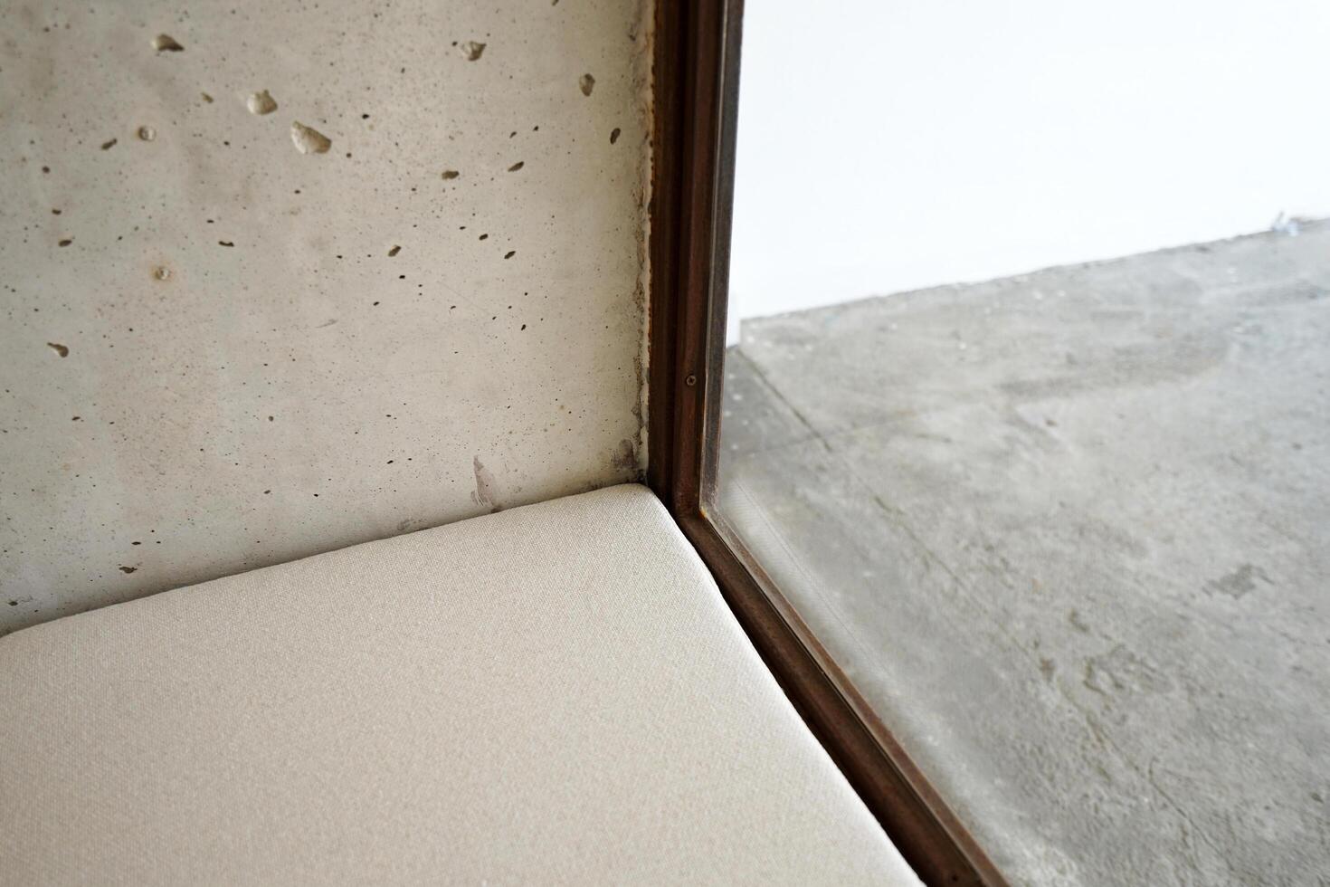 Interior loft room corner design decorated with cement concrete wall, white cushion chair and wooden mirror glass frame photo