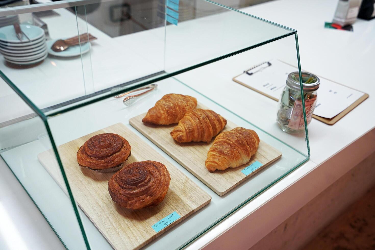 Butter plain croissants and cinnamon Danish rolls in bakery display showcase glass box photo