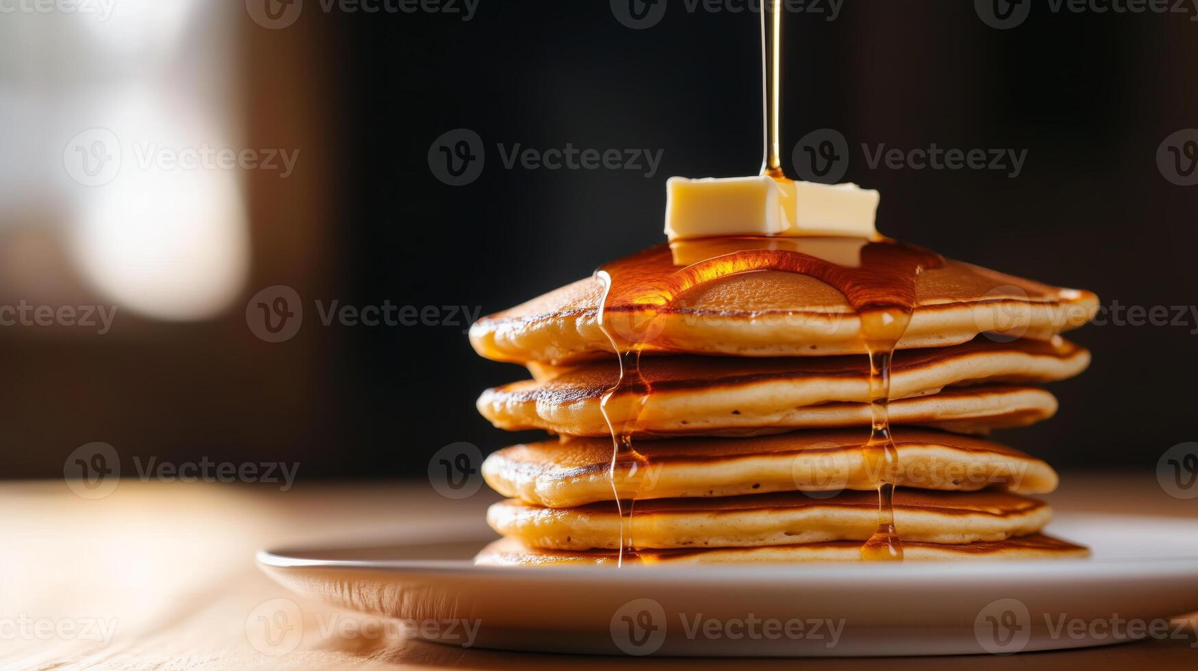 A stack of pancakes with syrup being poured on top photo