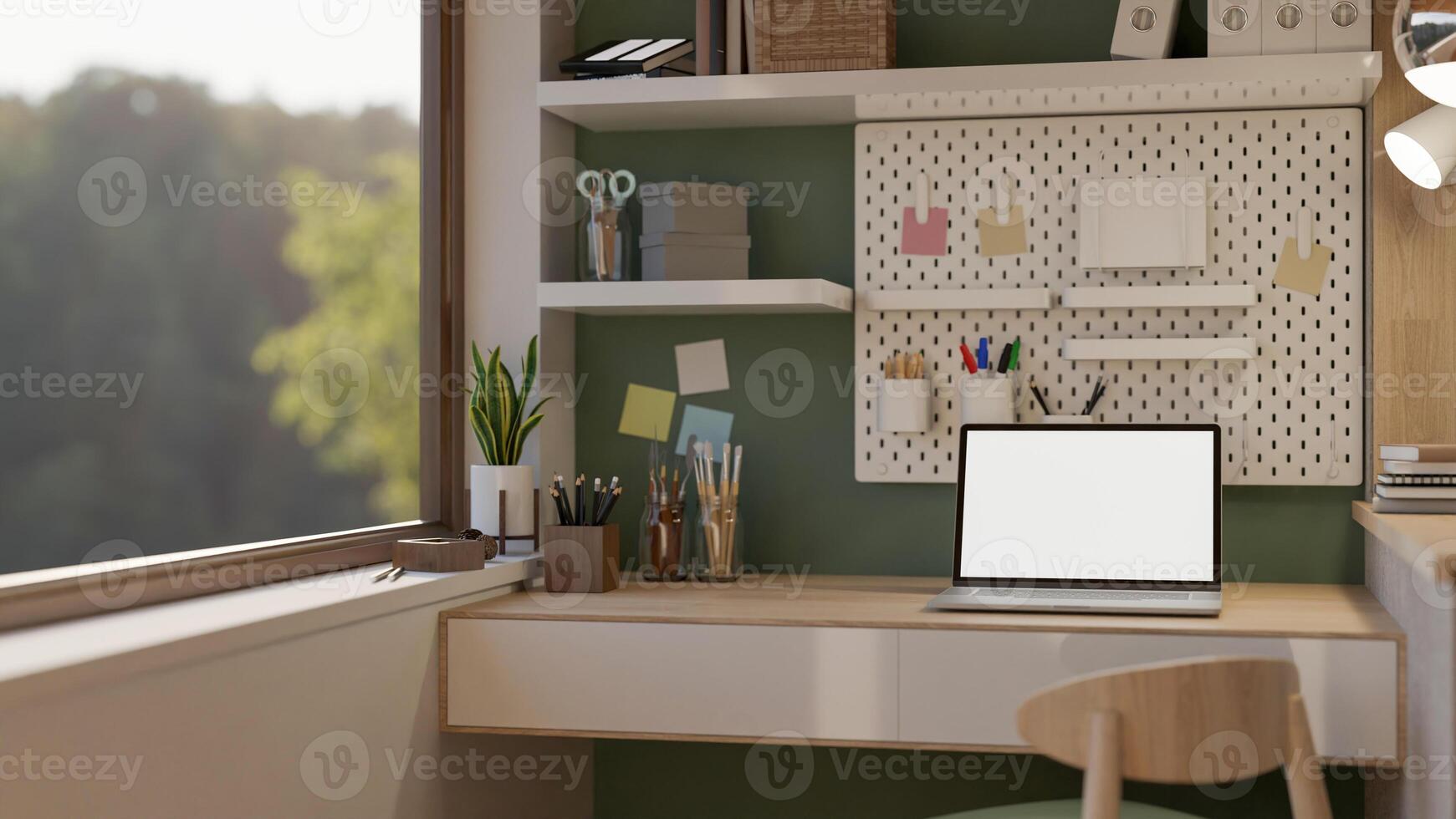 A white screen laptop on the wooden desk with stationary set and decors beside the large window. photo