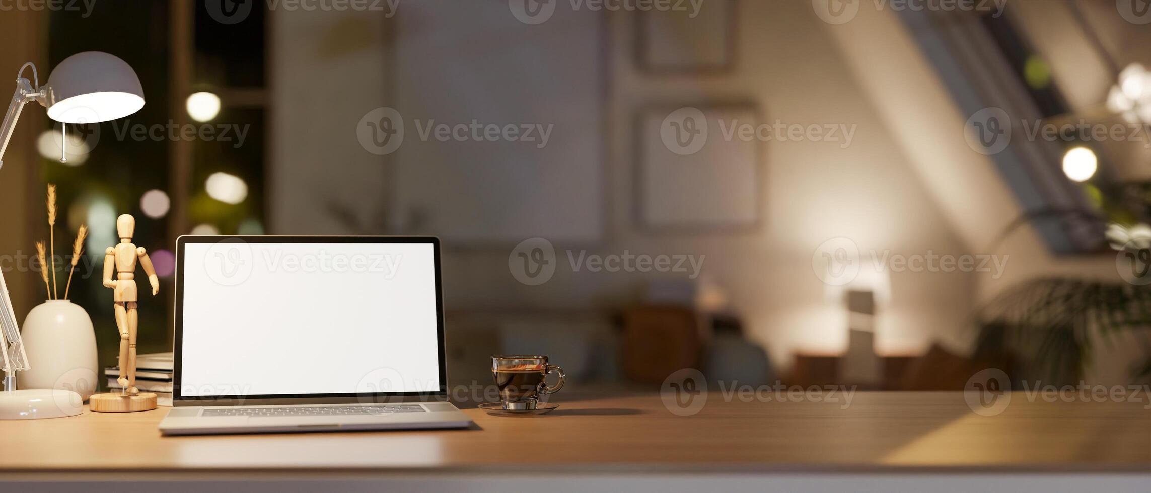 A white screen laptop on the wooden table in lamp light, with the blurred background of dim light room. photo