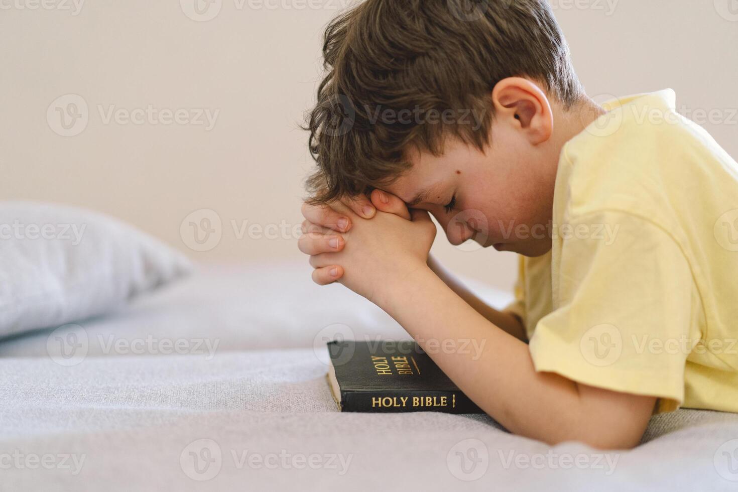 A boy with folded hands in front of him, he prays in his room. photo