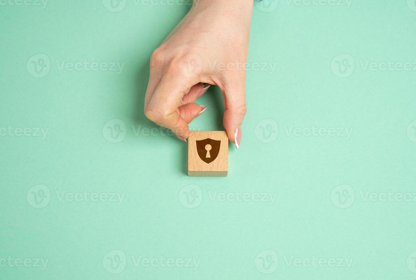 The hand places a figurine with a shield with a keyhole. Concept of protection and security. Secrets photo