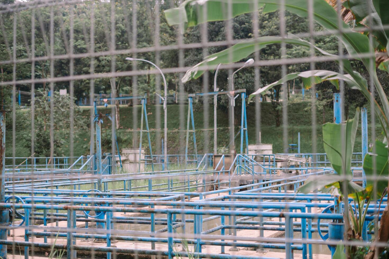 Wastewater treatment facility glimpsed through a security fence photo