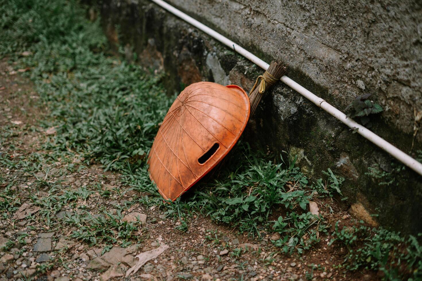 Rustic Conical Hat Resting on Grassy Patch Beside a Textured Wall photo