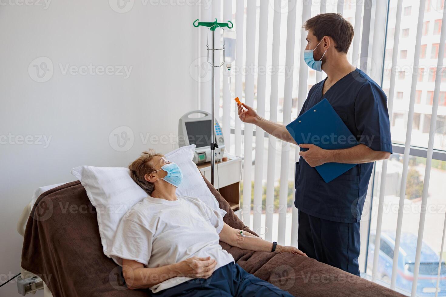 Doctor controls drip of her patient in mask during Covid-19 epidemic photo