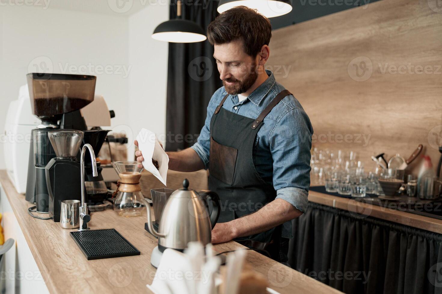 barista pours coffee beans into the coffee machine container for grinding photo