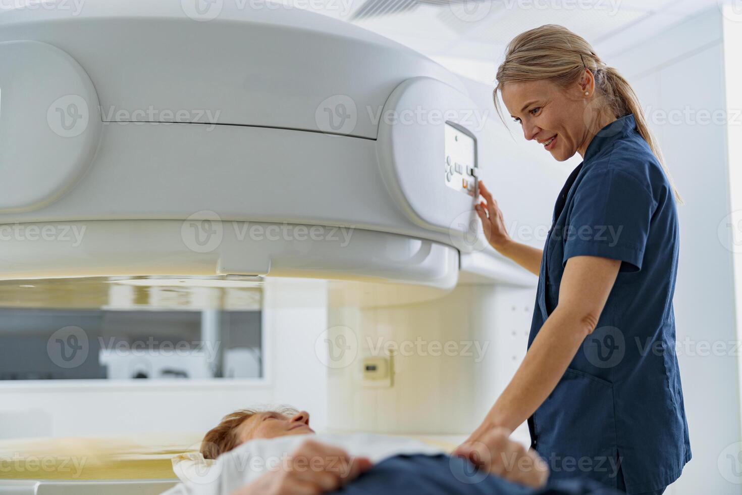 Radiologist controls MRI or CT or PET Scan with female patient undergoing procedure photo