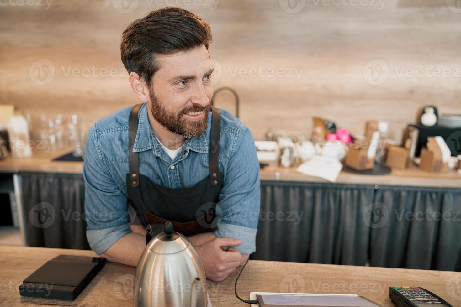 Smiling barista talking with client while standing behind a counter photo