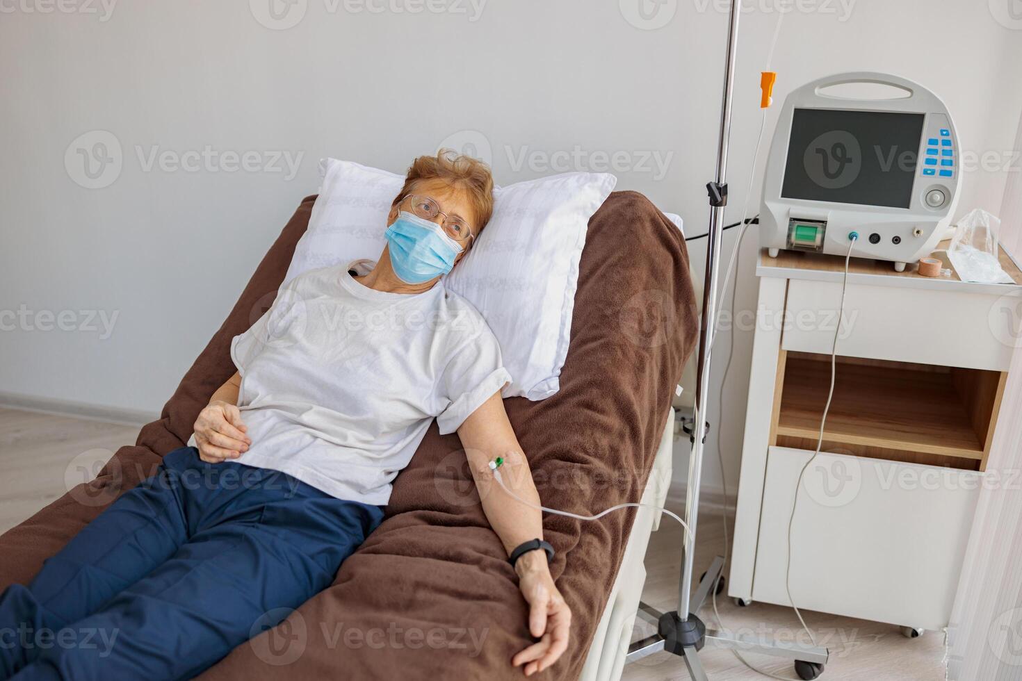 Sick patient in mask lying in hospital ward during medical procedure in clinic photo