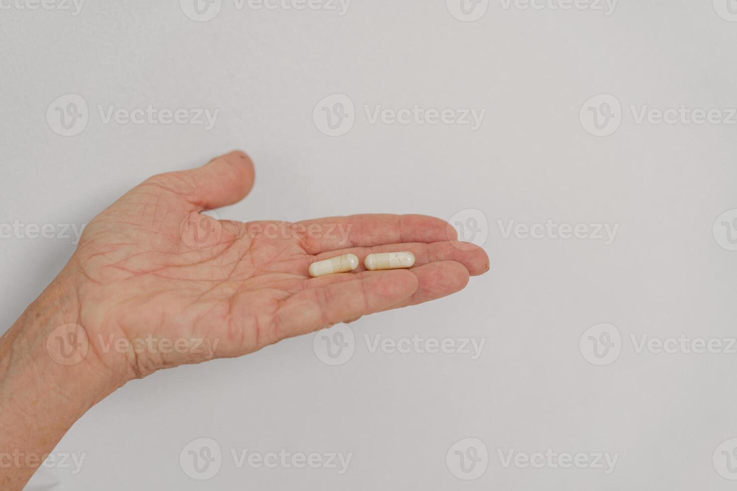 Person Holding Various Capsules in Hand Against a Plain Background of Neutral Color photo