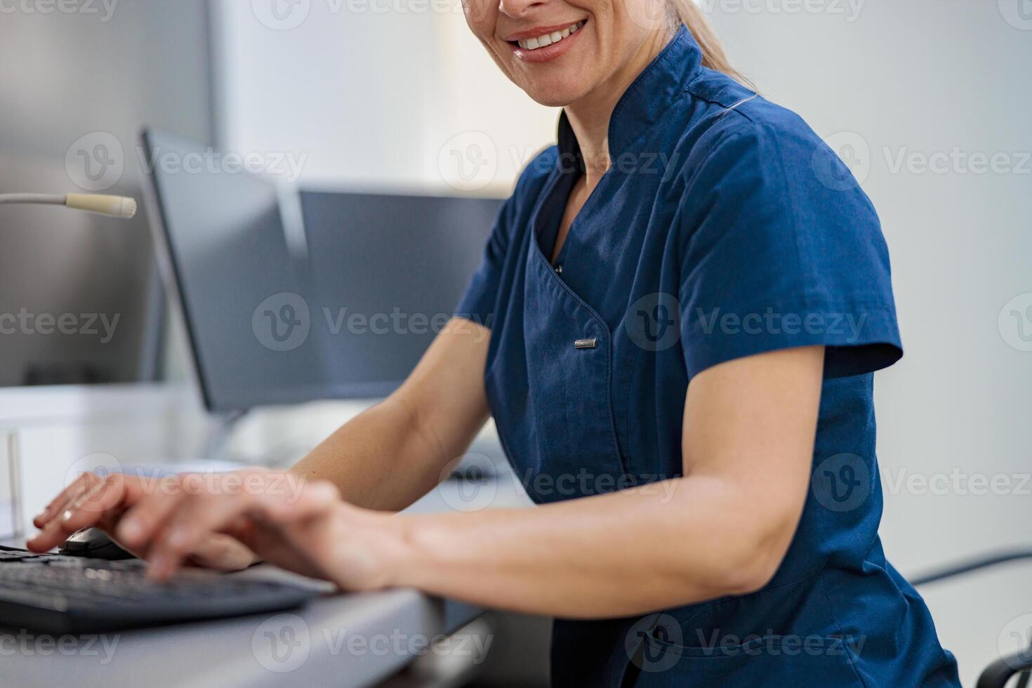 Close up of nurse on Duty working on computer at the Reception Desk in modern clinic photo