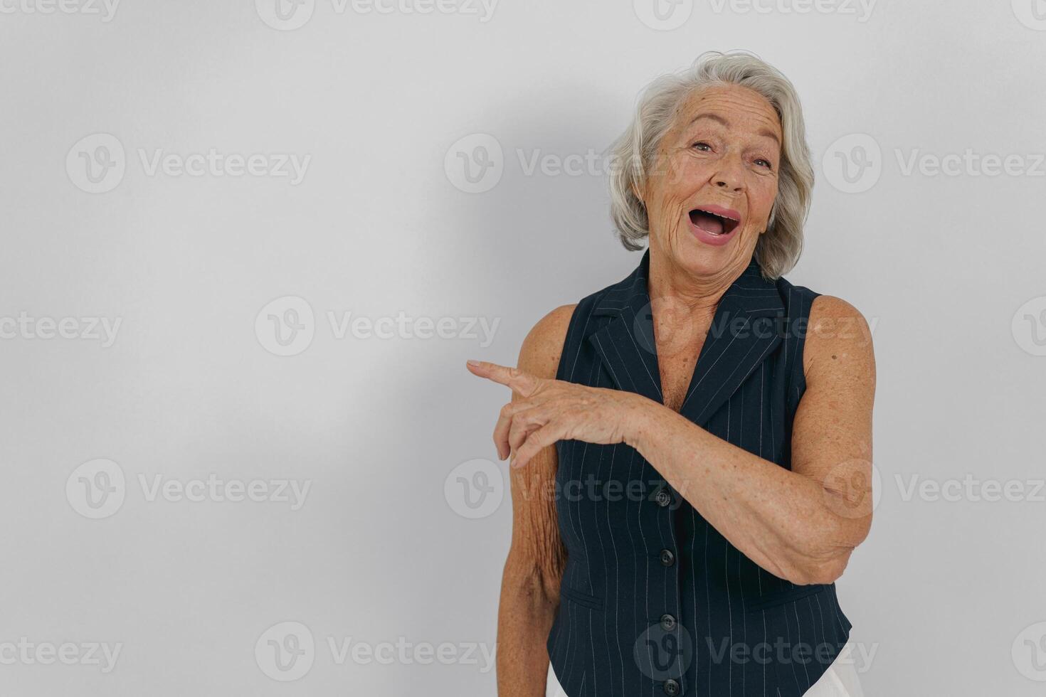 Energetic Senior Woman Pointing Enthusiastically with a Warm Smile and Joyful Expression photo
