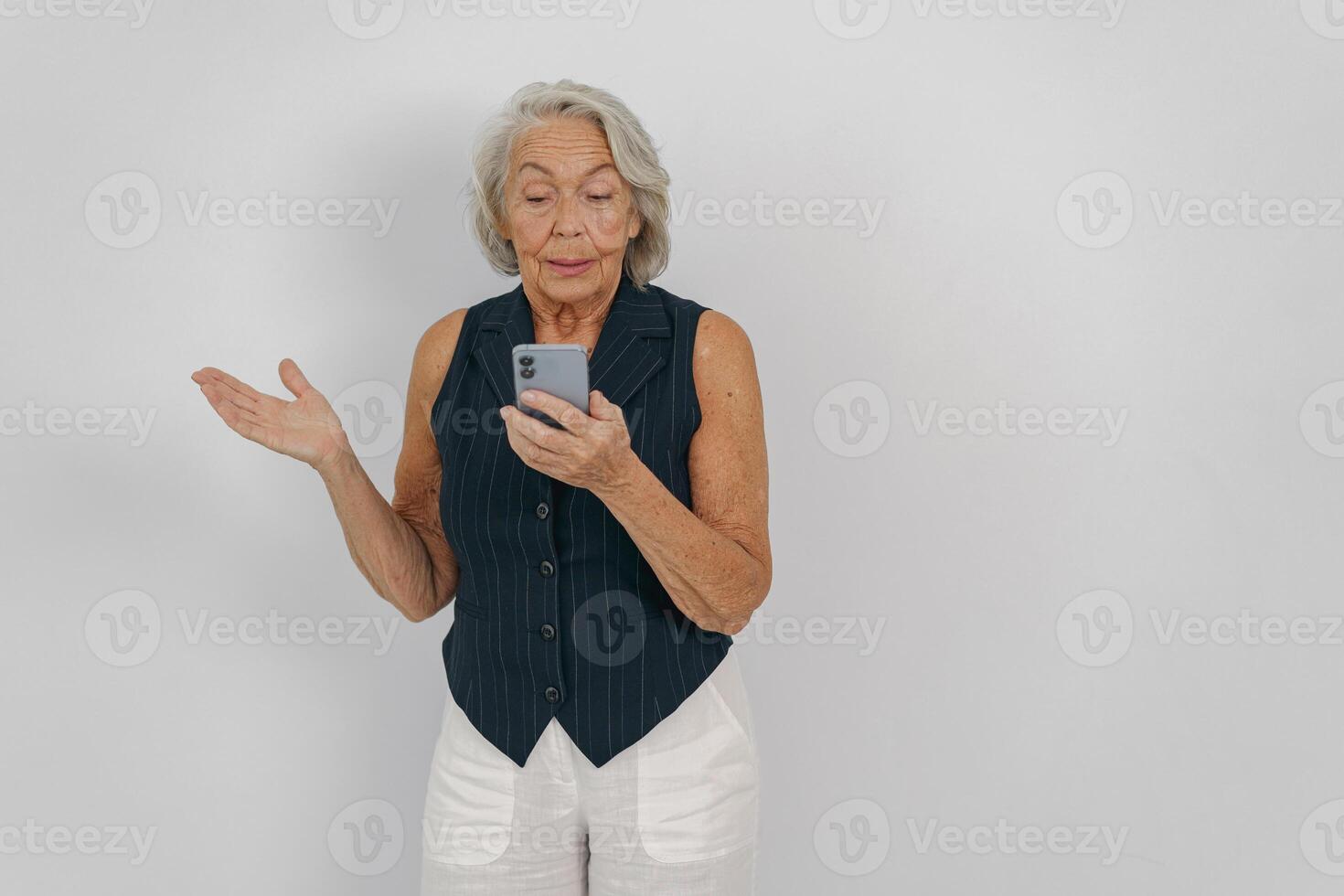 An Elderly Woman Actively Engaging with Her Smartphone in a WellLit Studio Environment photo
