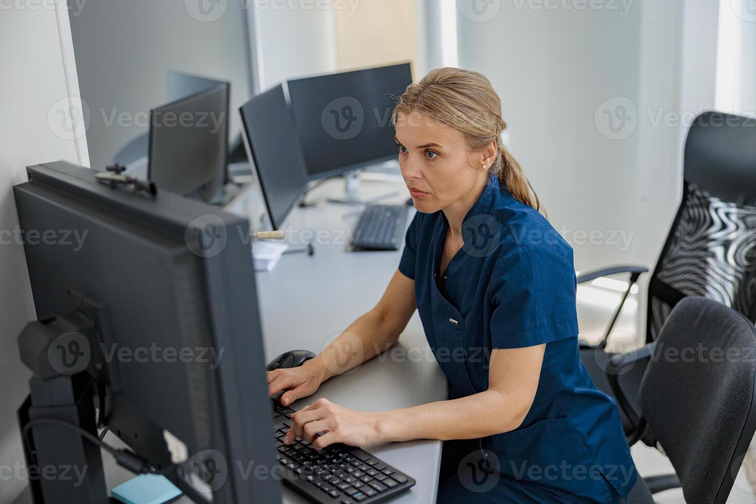 Nurse on Duty working on computer at the Reception Desk in modern clinic photo