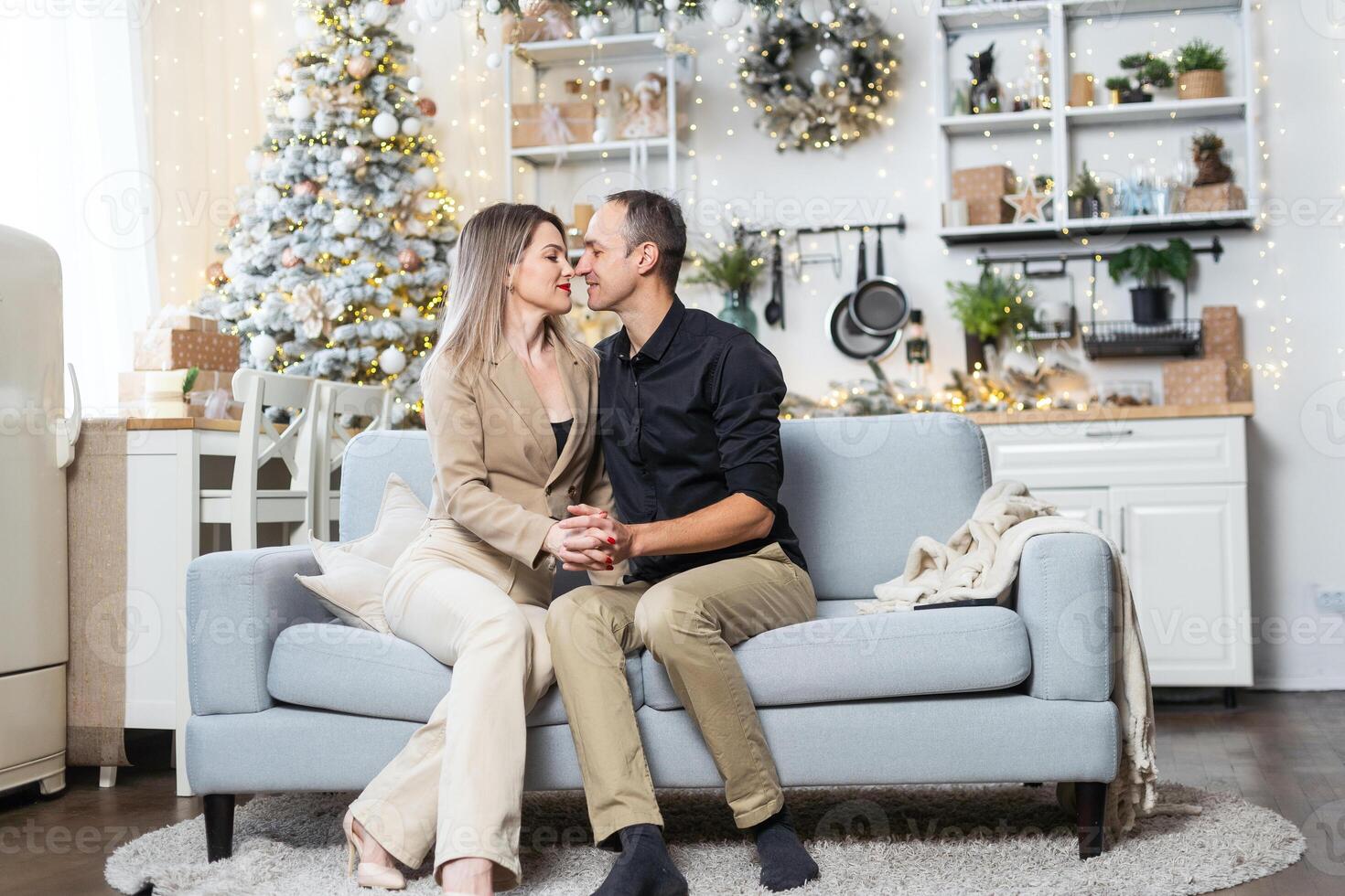 A happy couple shares a joyful moment while hanging, Christmas tree at home. photo