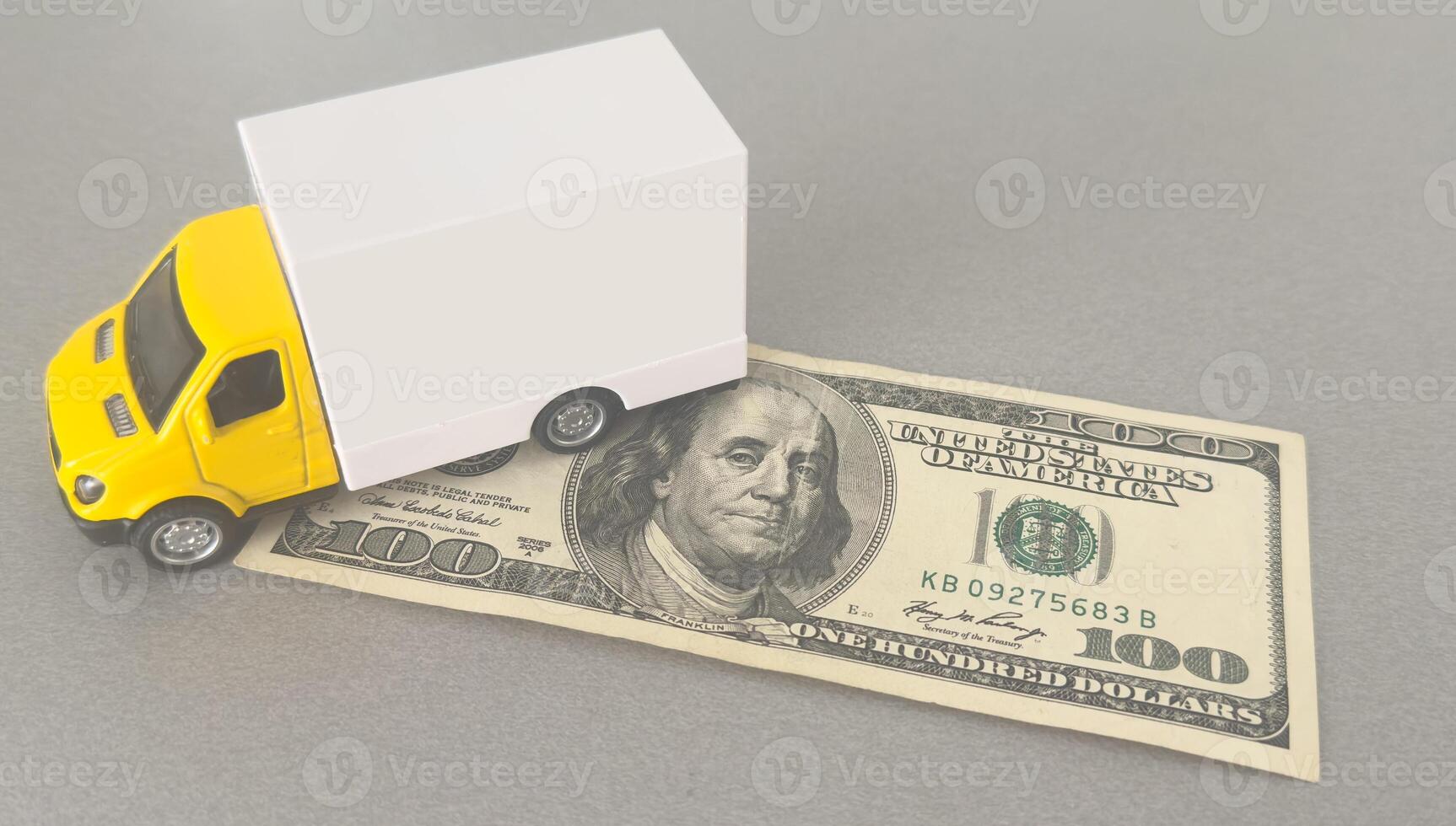 Delivery truck on hundred dollar bills banknotes. Background of moving or trucking concept close up photo