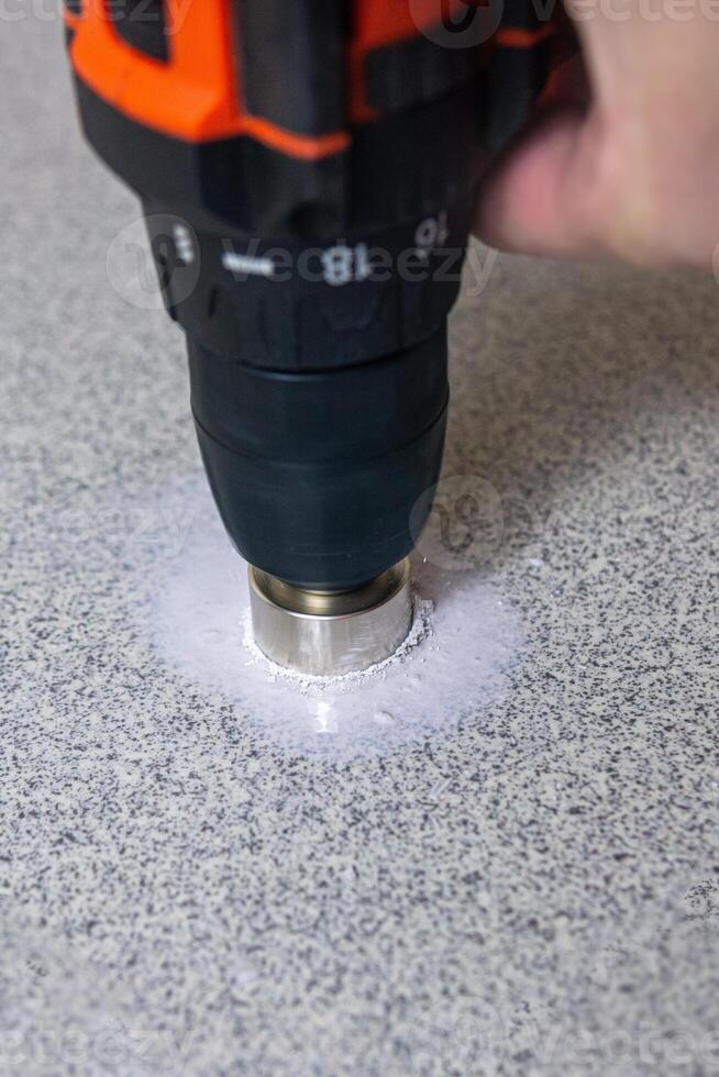 rotating diamond core hole saw drilling into a stone slab photo