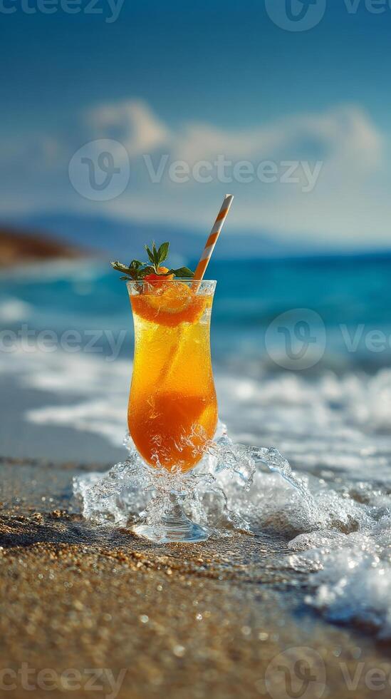 Refreshing orange cocktail on sandy beach with ocean waves splashing around photo
