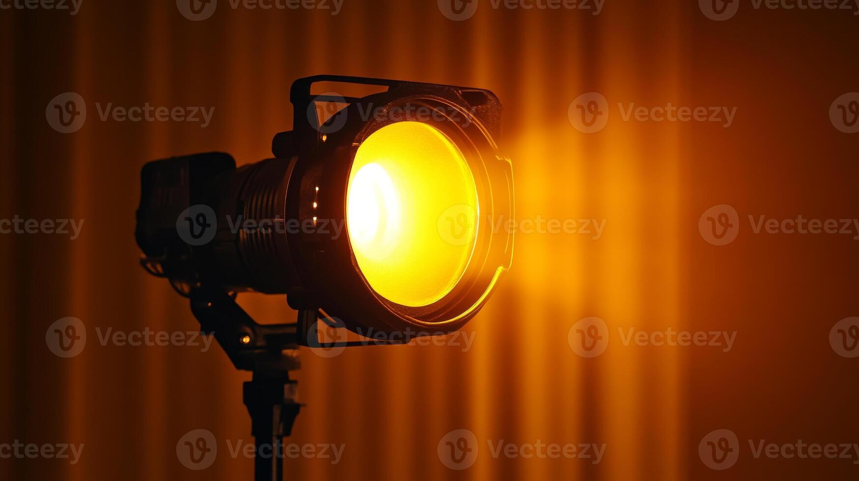 Studio spotlight shining bright with a warm yellow glow in a dark room photo