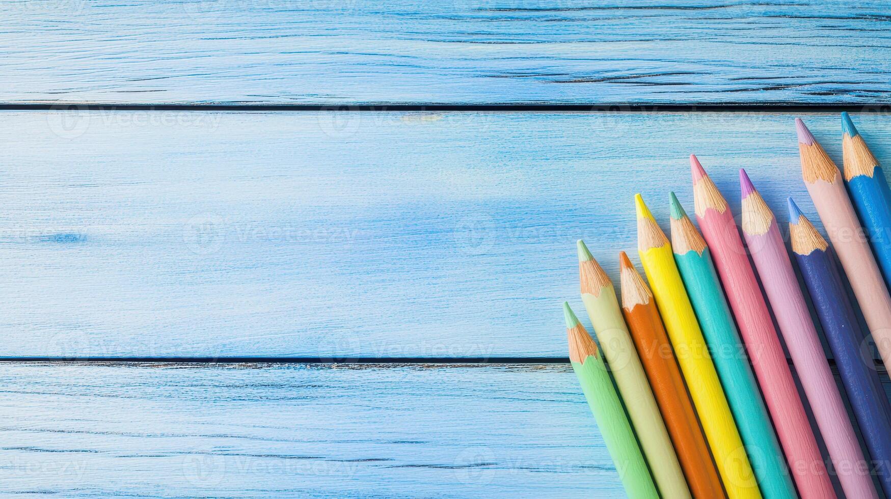 Colorful pencils arranged on blue wooden surface photo