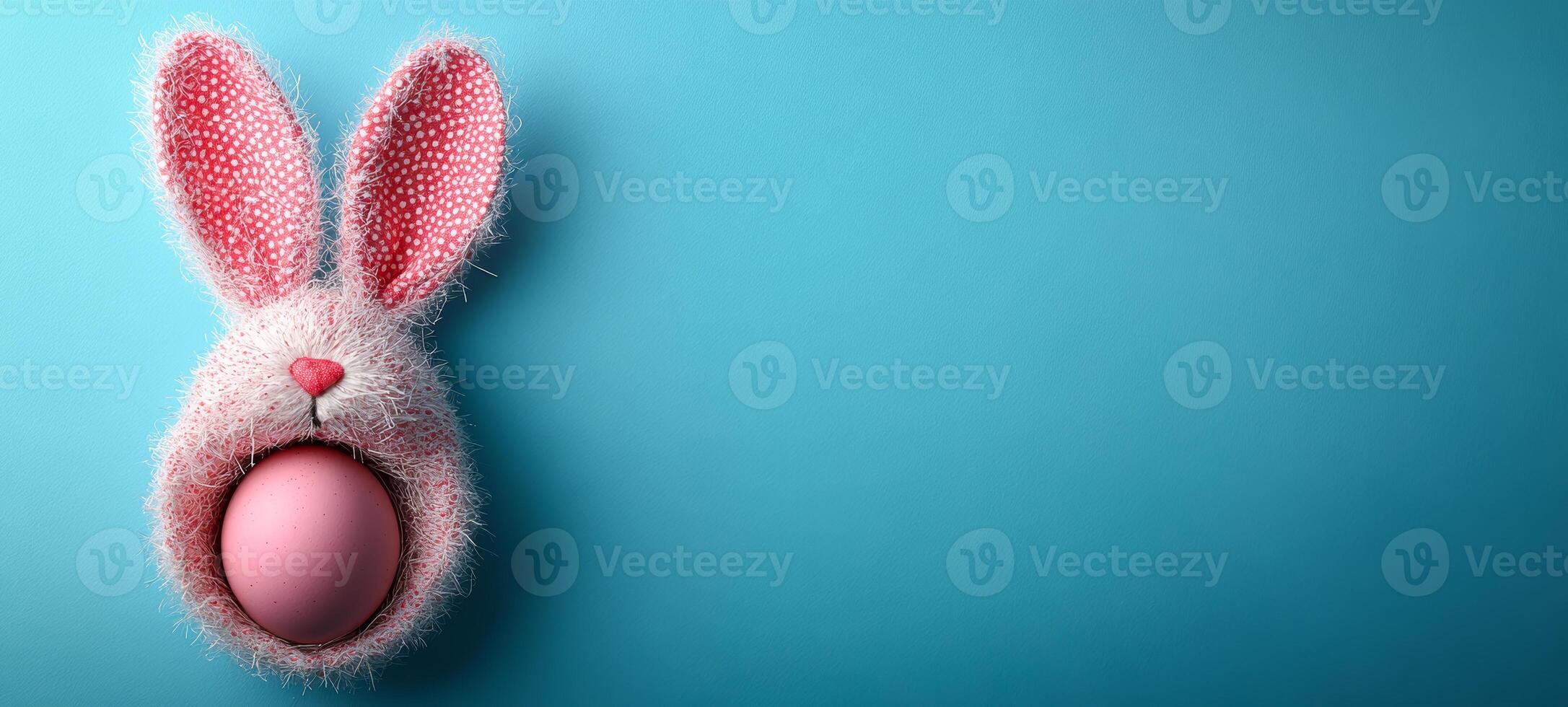 Colorful bunny decoration with egg. A fluffy bunny-shaped decoration holds a pink egg against a serene blue background, perfect for spring festivities. photo