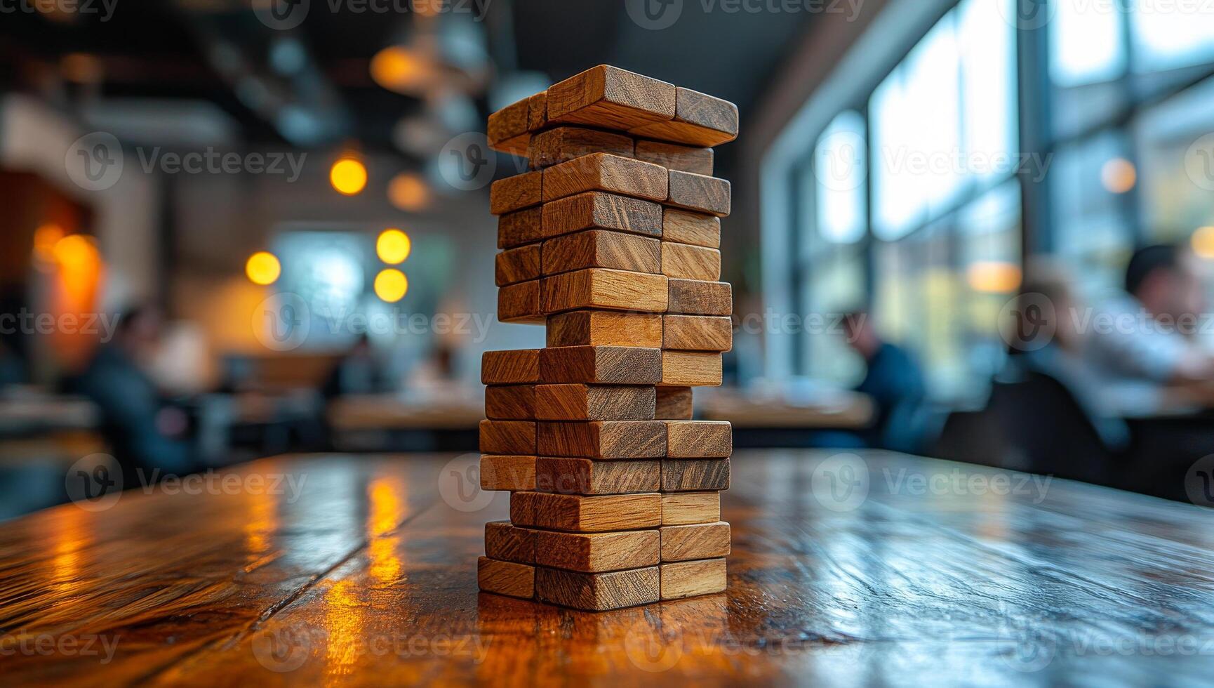 Wooden game tower stands tall in cafe. A group of people play a stacking game with wooden blocks in a bustling cafe during the evening hours. photo