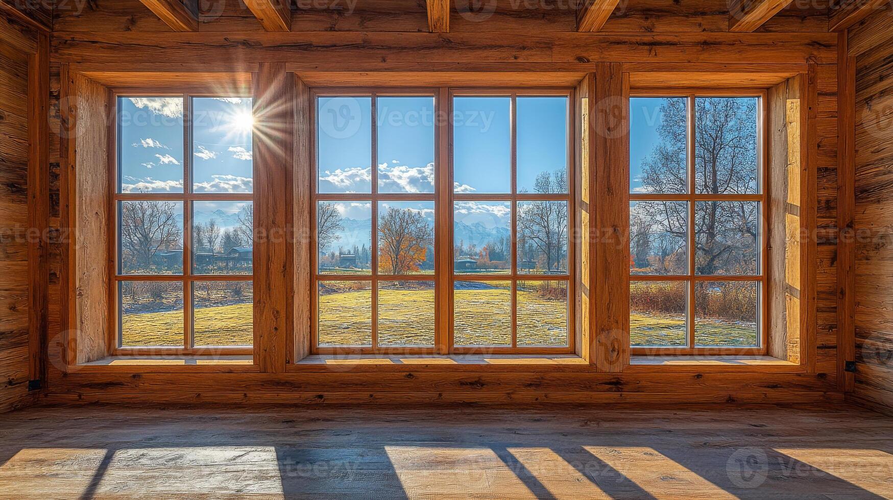 Stunning cabin window view. Sunlight streams through large windows, highlighting a scenic landscape of trees and fields beyond the cabin. photo
