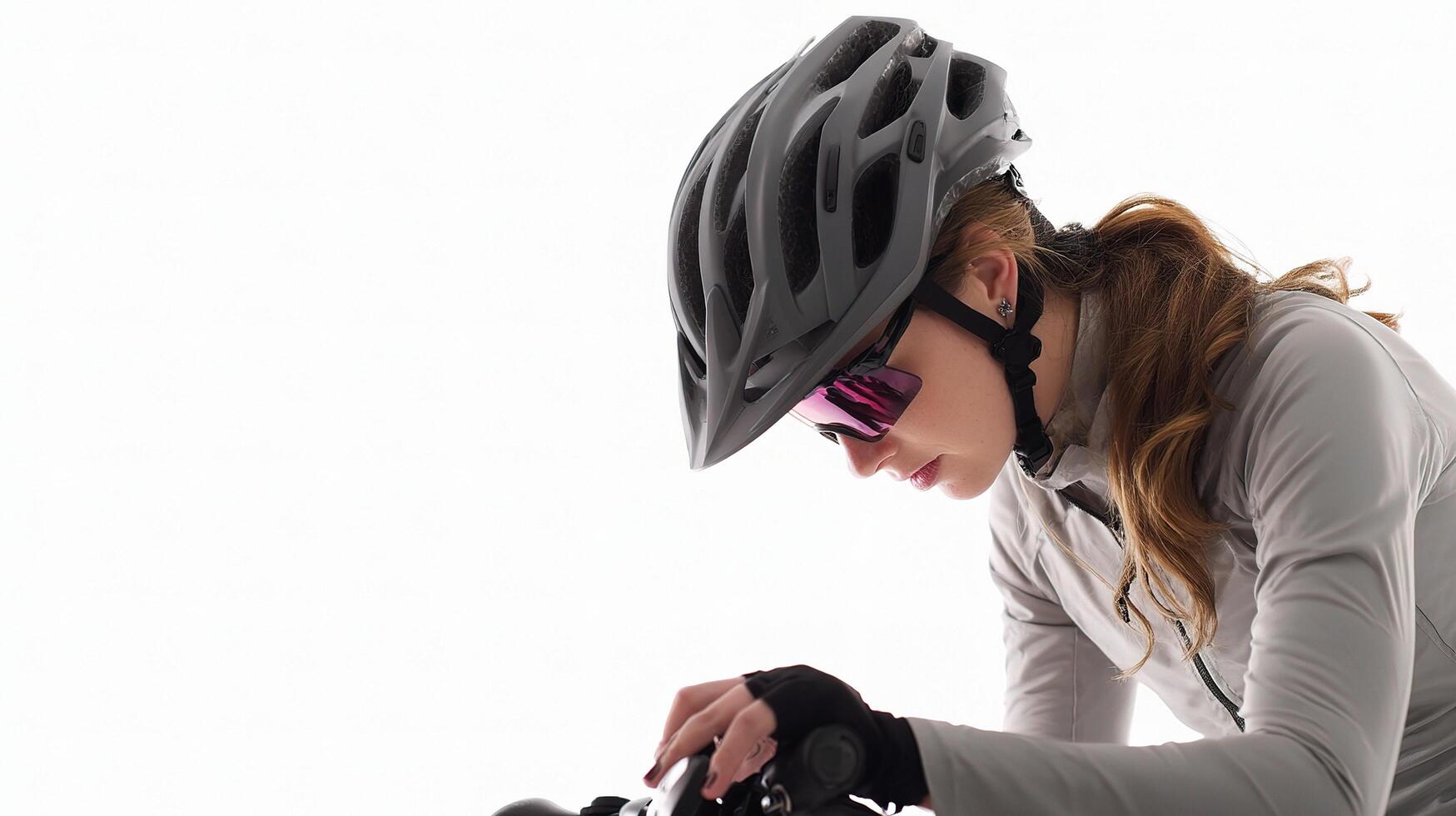 A woman wearing a helmet and sunglasses is riding a bike photo