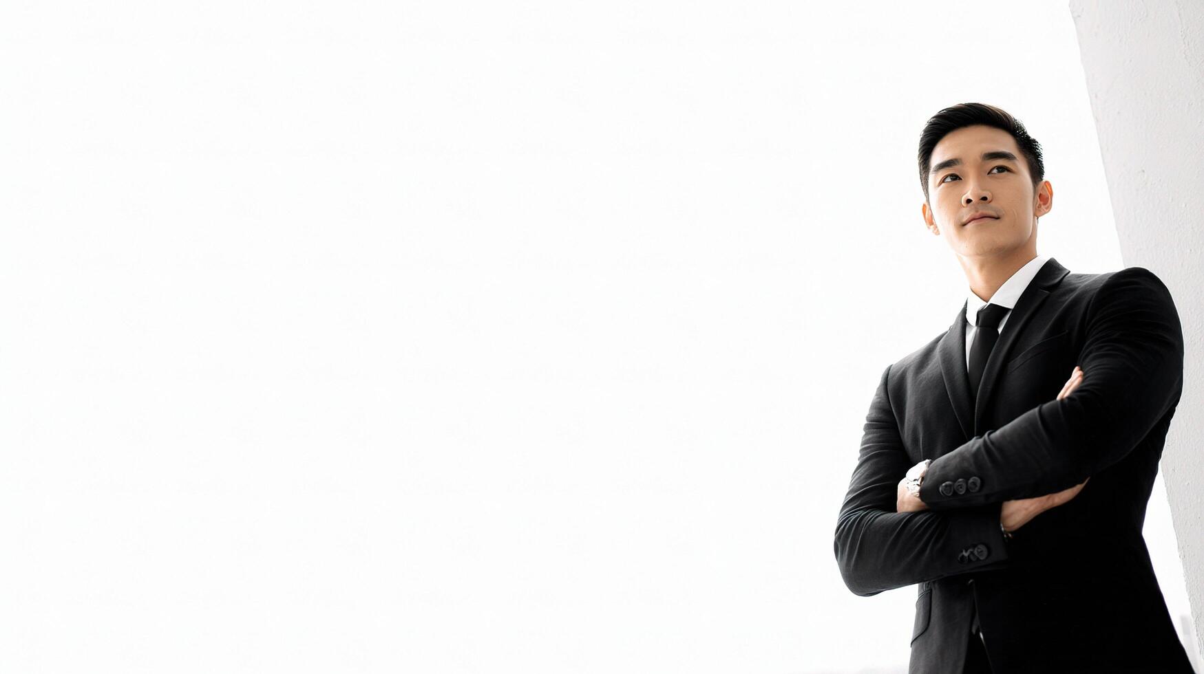 Asian man in suit standing with arms crossed photo