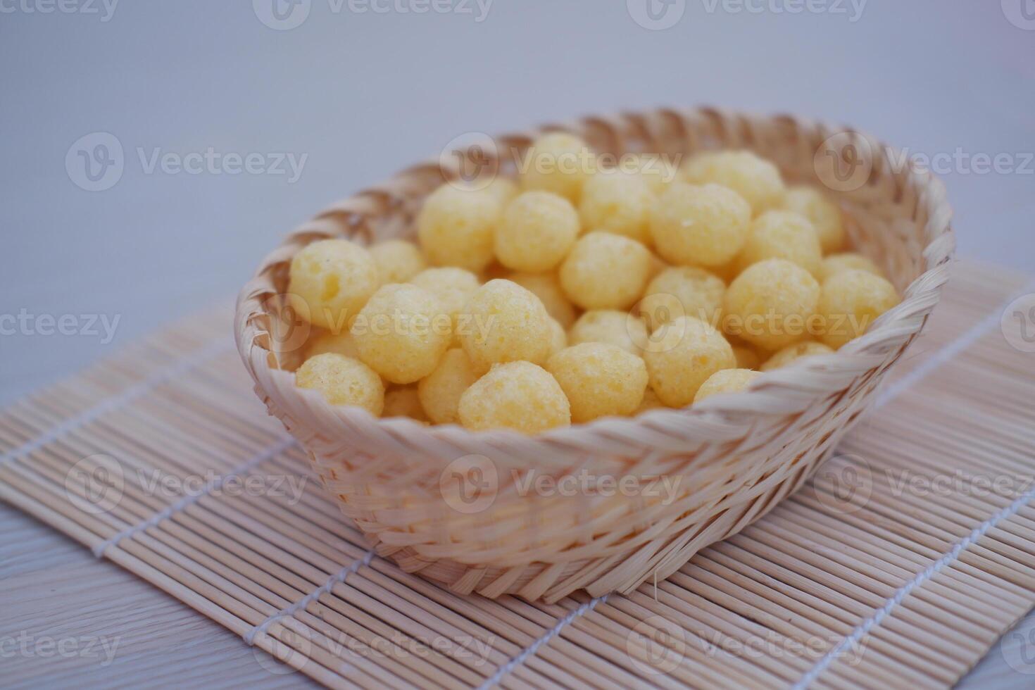 a small woven basket filled with round, yellow, puffed corn snacks photo