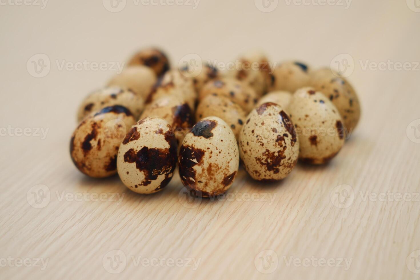 a cluster of quail eggs arranged neatly on a light wooden surface photo