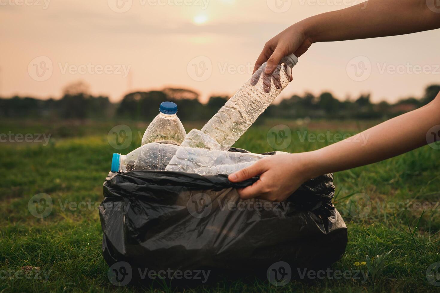 A person is holding a plastic bottle in a trash bag photo