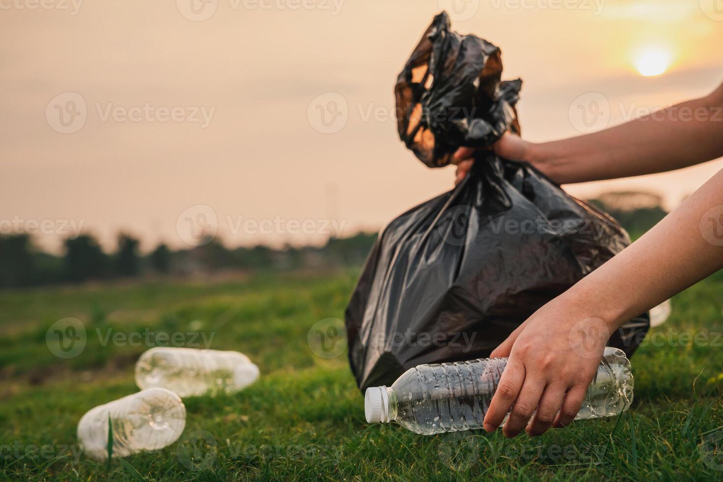 A person picking up a plastic bag with a bottle of water photo