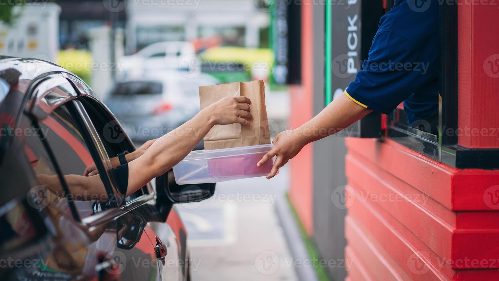 A person handing a bag to a car window photo