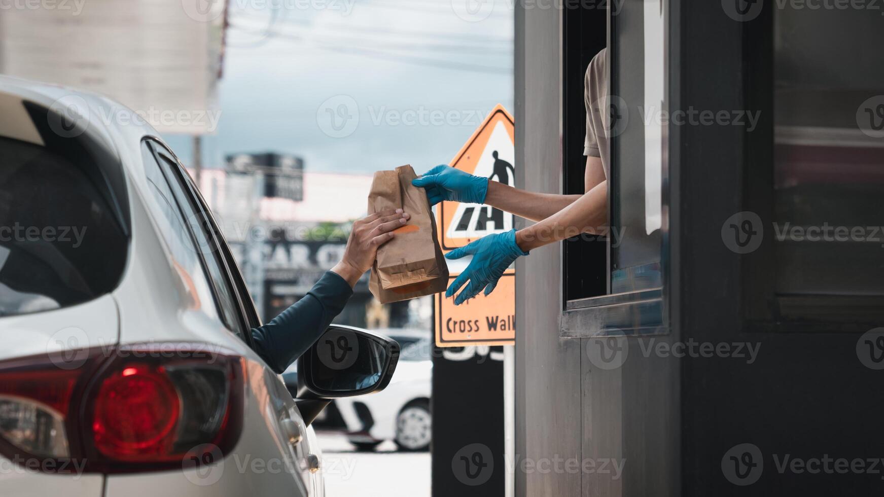A person handing a bag to a person in a car photo