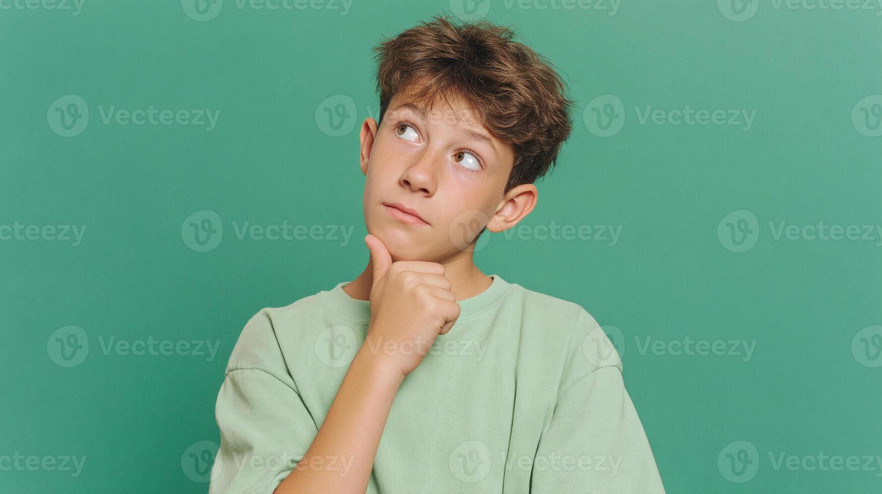 A boy is looking up at something on a green background photo