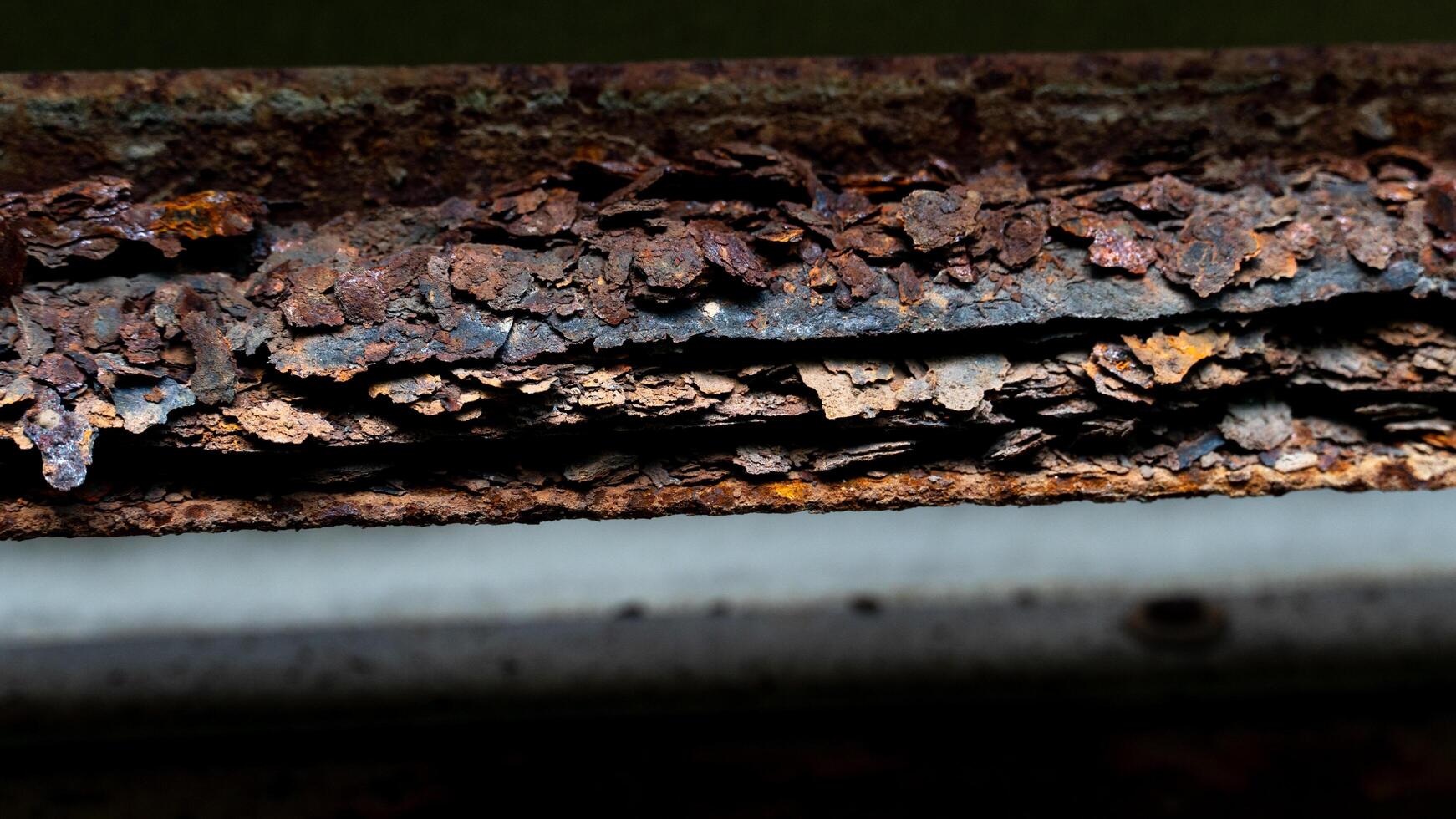 Heavily rusted and corroded metal surface. Layers of peeling. Reddish brown rust are prominent. indicating significant exposure to moisture and the elements. photo