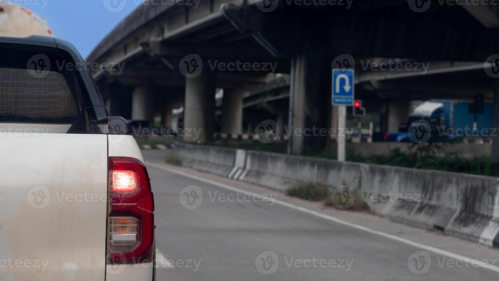 Rear side view of pickup car white color. A car slightly contaminated with mud. Stopped at a traffic light on the side of a concrete overpass. photo