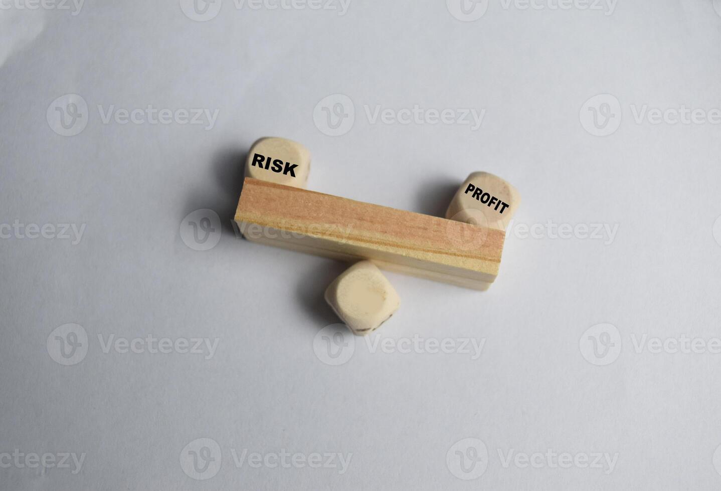 Words profit and risk are written on a seesaw made of wooden blocks on the white background. concept of profit and risk analysis in business or risk management photo