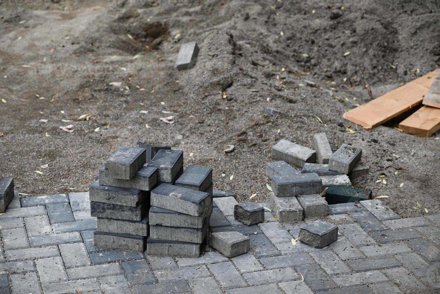 Low angle view of male hands measuring and leveling sand and cement tiles for precise pavement of the outside patio or sidewalk. Construction industry and renovation. photo