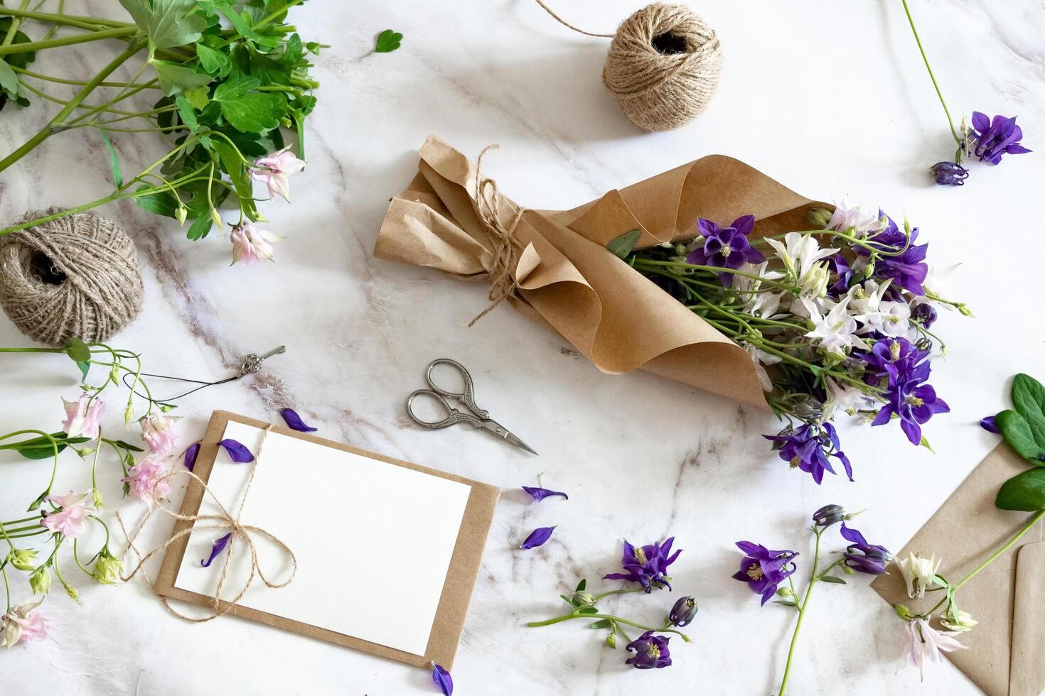 The image displays a flat lay composition of floral arranging supplies on a marble surface. photo