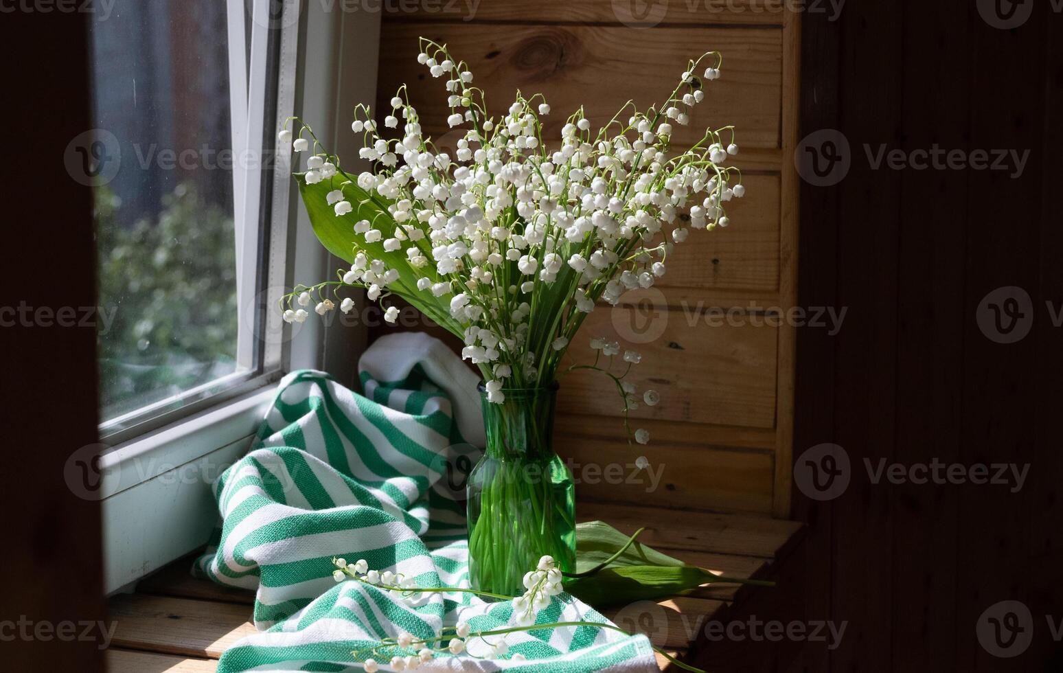 Bouquet white flowers Lily of the valley in glass Convallaria majalis, May bells, may-lily on a white table with space for text photo