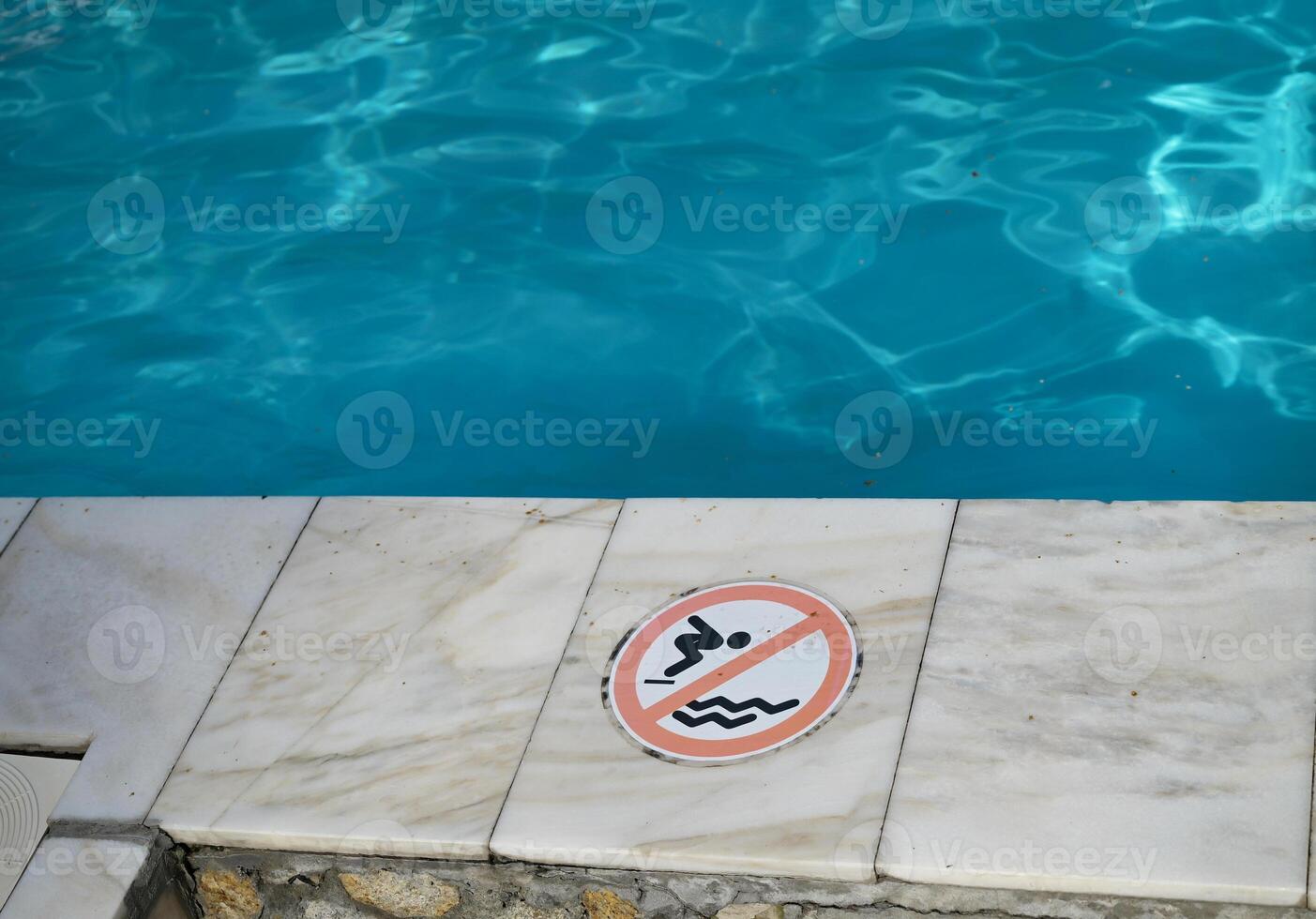 Do not jump into water sign on ground near swimming pool. Danger. photo